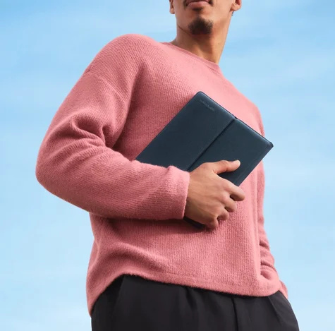 一名身穿粉紅色毛衣的男子緊緊拿著一個袖珍文件夾。