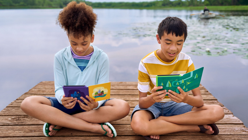 孩子們坐在湖邊閱讀 Kindle Paperwhite Kids。