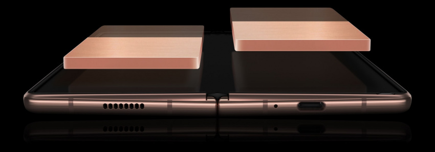 展開並機面朝上平躺的亮光銅Galaxy Z Fold2 5G。兩邊的全日雙電池懸浮展示在主屏幕上方，圖像褪色，以展示雙電池如何合一運行，均衡輸出電量。