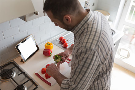 Man using a tablet to display a recipe online while he cooks